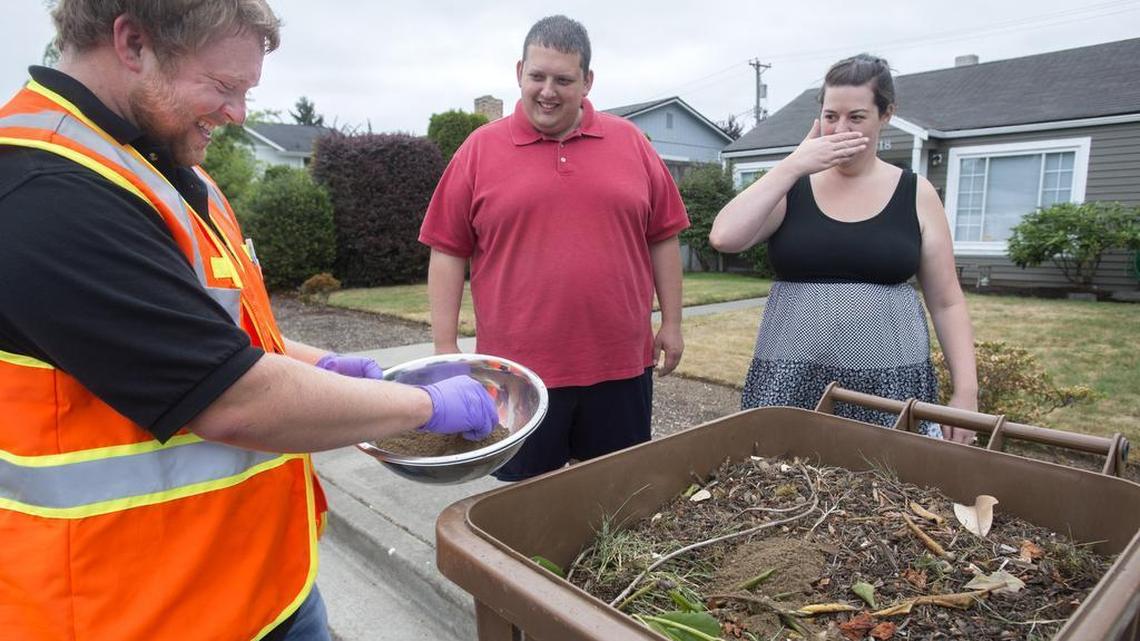 Tacoma-Pierce County Health Department Environmental Health Specialist Jeremy Bush clears the rocks from a soil sample at the home of Bryce and Alex Stillman in Ruston on July 7. Alex shields her nose from breathing soil possibly contaminated with lead and arsenic.