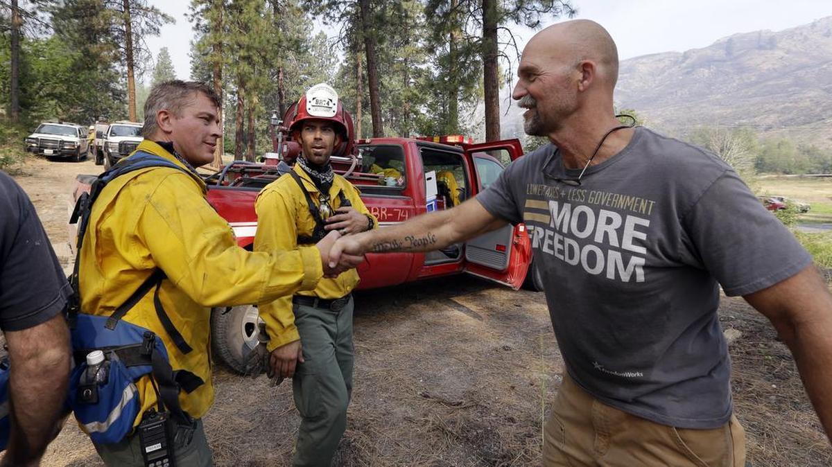 
Homeowner Brad Craig, right, thanks departing firefighters who he said saved his home from a wildfire Saturday morning in Okanogan. 
