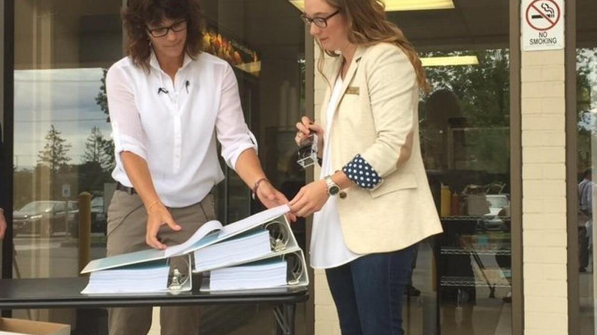 Fircrest resident Cheryl Iseburg, left, signs the formal statement of charges in a recall petition against Pierce County Prosecutor Mark Lindquist as Whitney Rhodes, assistant to county auditor Julie Anderson, prepares to stamp the petition in June.