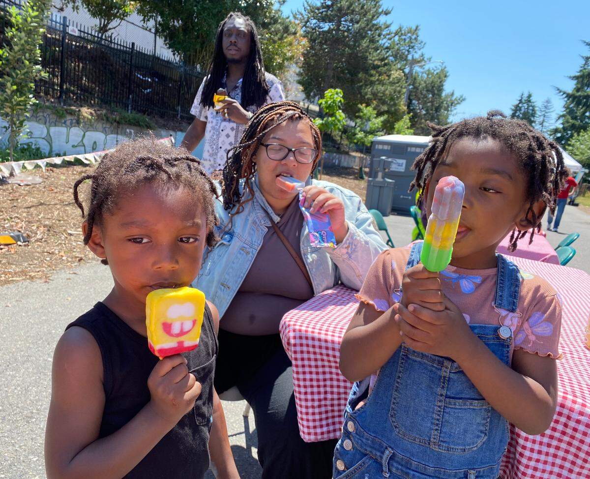 Khairo Malik-Harris, left, 3, sister Khairo, 5, and mom Alexis Malik enjoy free popsicles at Saturday’s South End block party on D Street. Dad Shawn Harris (background) works at Holiday Inn, one of the event’s sponsors.