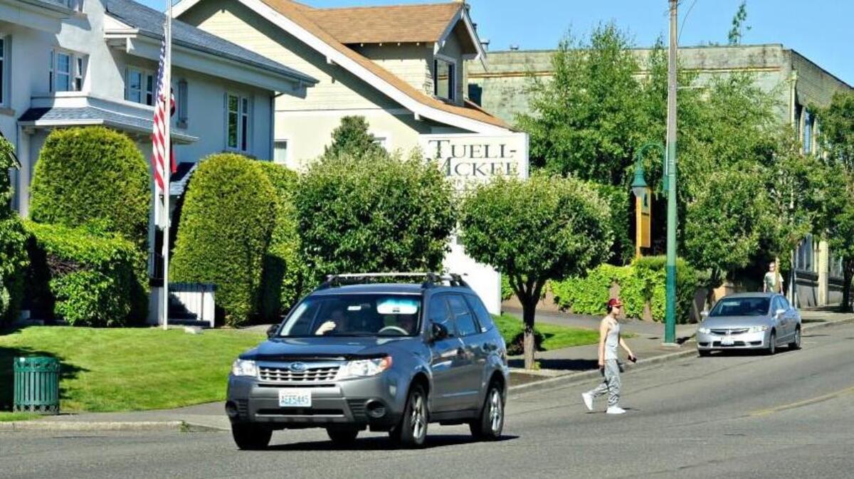 A pedestrian crosses 6th Avenue in Tacoma using an unmarked crosswalk in June 2016. People can use the Tacoma 311 service to request that the city mark a crosswalk.