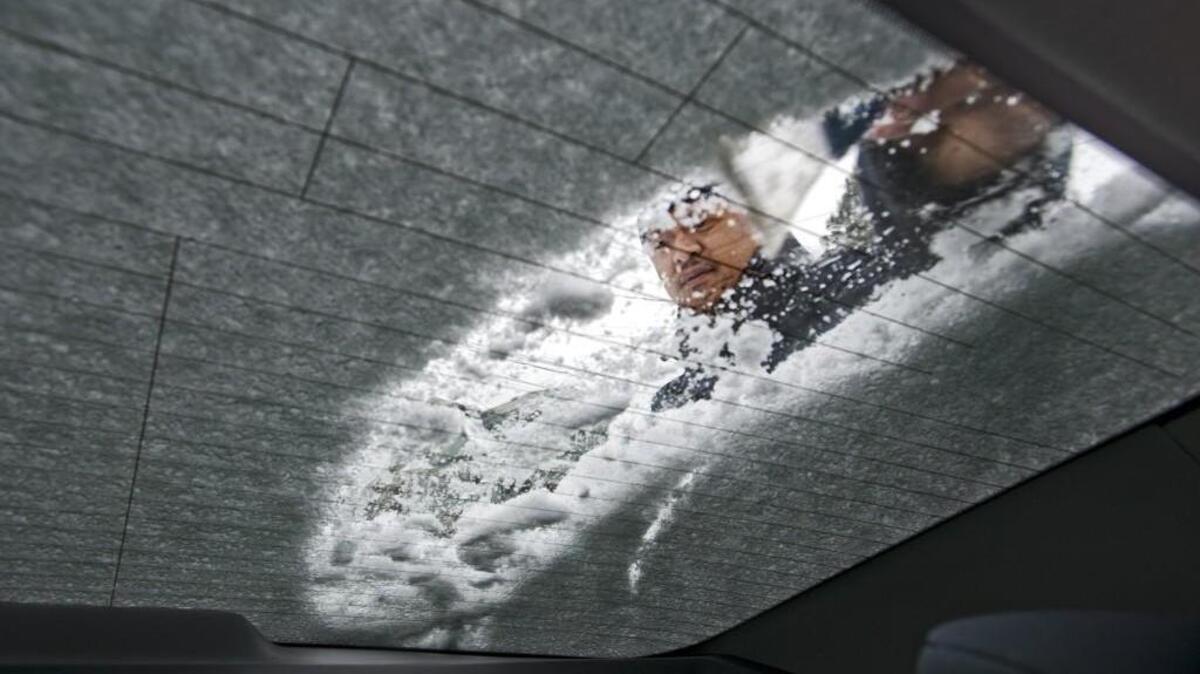 John Scanlan scrapes snow off his car window in South Tacoma in 2014.