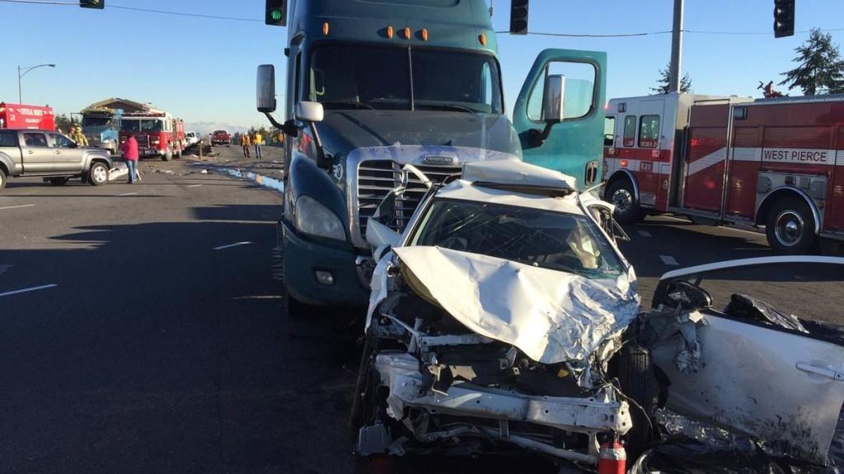 A smashed car and a semitruck sit on state Route 512 on Thursday afternoon after being involved in a three-vehicle wreck that snarled traffic on the highway and Interstate 5 for hours. The semitruck driver was arrested on suspicion of vehicular assault, according to the Washington State Patrol.