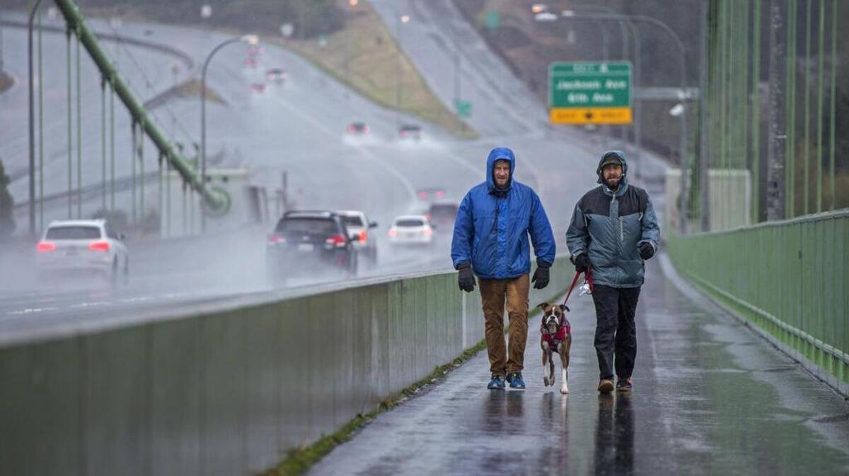 In spite of the heavy rain, Mike Przekwas, Margo, and Jeff Johnson make their annual walk across the Tacoma Narrows Bridge on Thanksgiving.