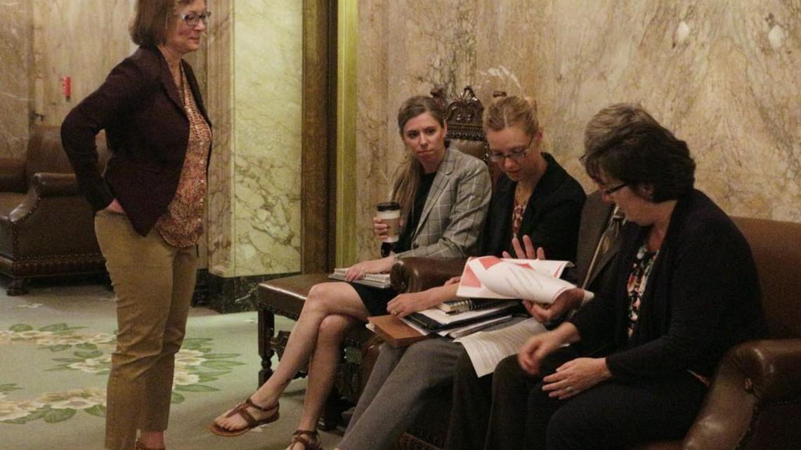 Democratic state Rep. June Robinson, standing, talks with fellow Democratic budget negotiators, Reps. Kristine Lytton and Timm Ormsby, seated right, and staff in the House wings before heading into a meeting to brief fellow lawmakers on the details of a state budget deal, Thursday, June 29, 2017, Olympia, Wash. A new two-year budget must be signed into law by midnight Friday in order to avoid a partial state government shutdown. (AP Photo/Rachel La Corte)