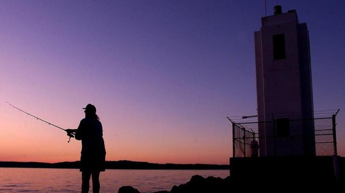 A waning sunset provides enough light for Derald Pearce to continue fishing for salmon near the Brown's Point Lighthouse.