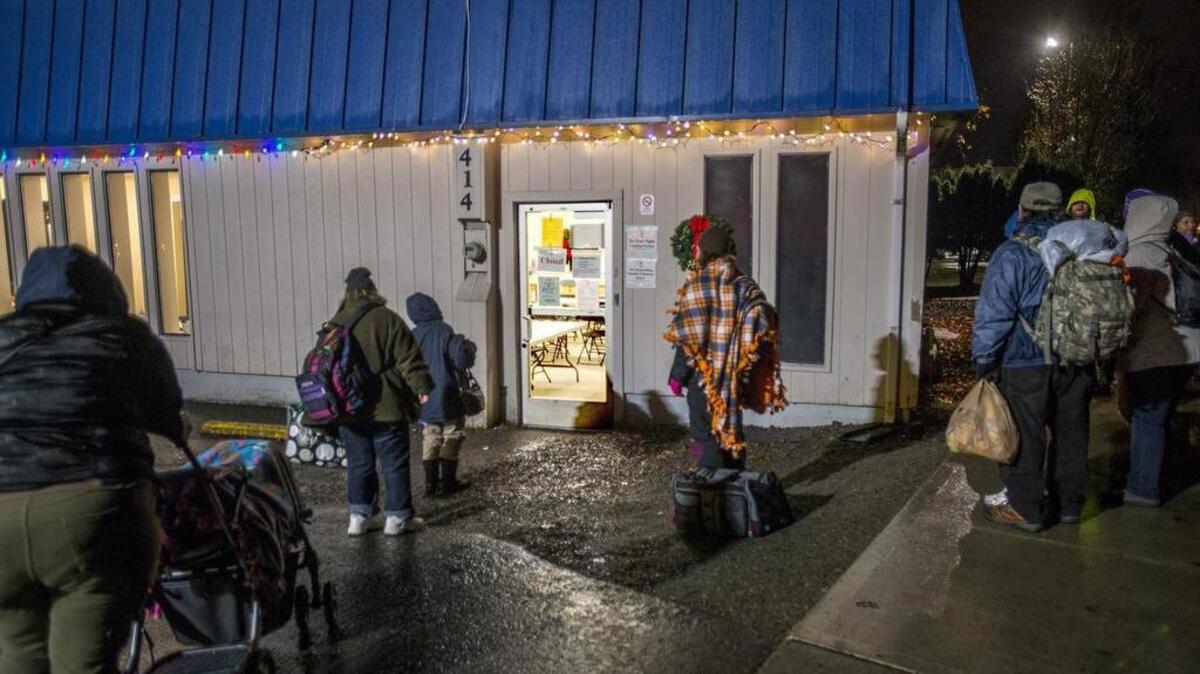 A couple dozen homeless people wait for New Hope Resource Center in downtown Puyallup to open at 5:30 p.m. as part of its Freezing Night Program in December. The city has imposed a new security rule on the center, and the center has agreed to abide by other new rules.