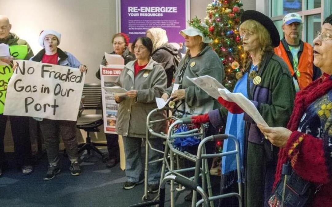 About 20 demonstrators sing in the the Puget Sound Energy office on South 38th in Tacoma on Dec. 22, 2016. Their songs were Christmas carols with original lyrics opposing the Liquefied Natural Gas plant that PSE is building on Tacoma's tideflats.