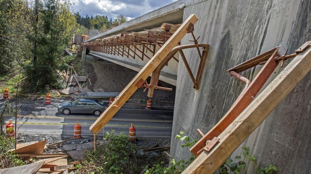 
Many broken timbers and bent steel brackets hang on the side of the state Route 410 overpass above Angeline Road East in Bonney Lake on April 14, 2015. The prior day the concrete wall fell off the overpass from where construction had been in progress, killing a young family of three that was driving underneath in their pickup truck.
