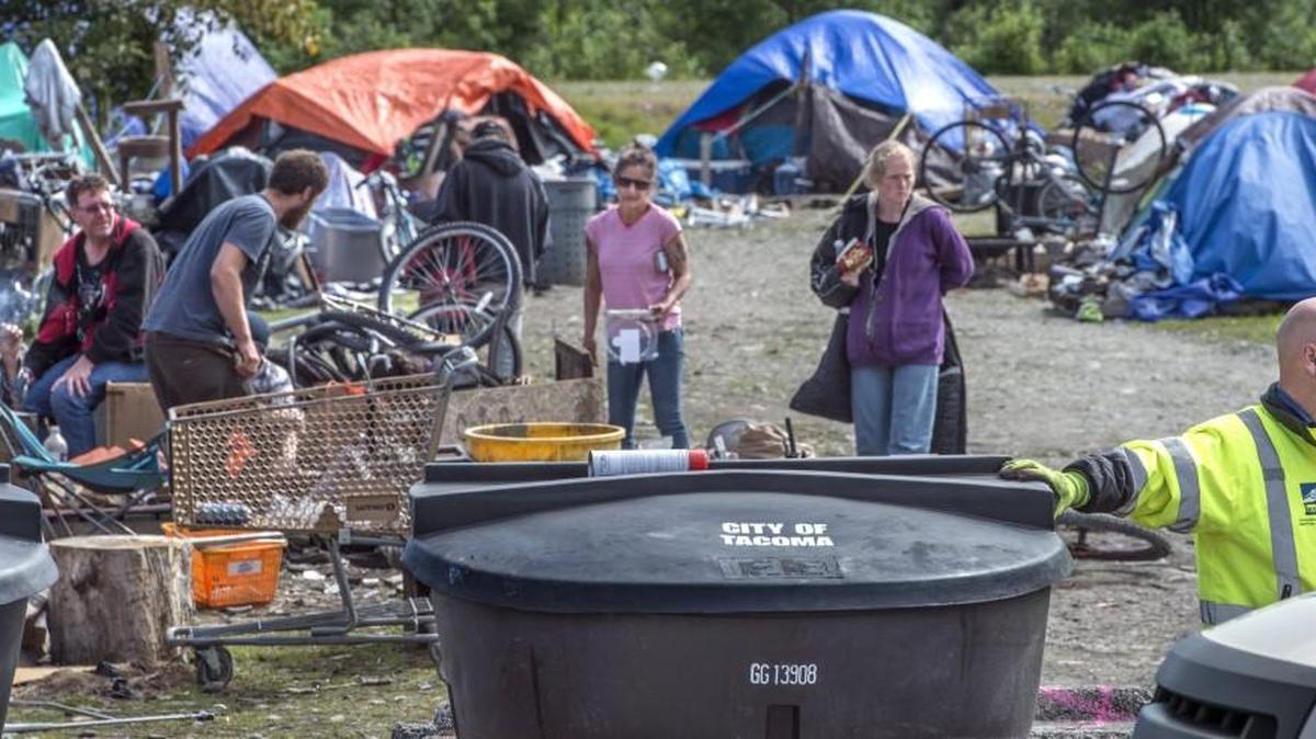 Tacoma solid waste management worker Lyle Hovenstein, right, installed three large trash bins for use by homeless people at a camp near Portland Avenue and 18th Street East in May 2017. City staff has recommended spending upwards of $7 million in 2018 to continue addressing the city’s homelessness crisis.