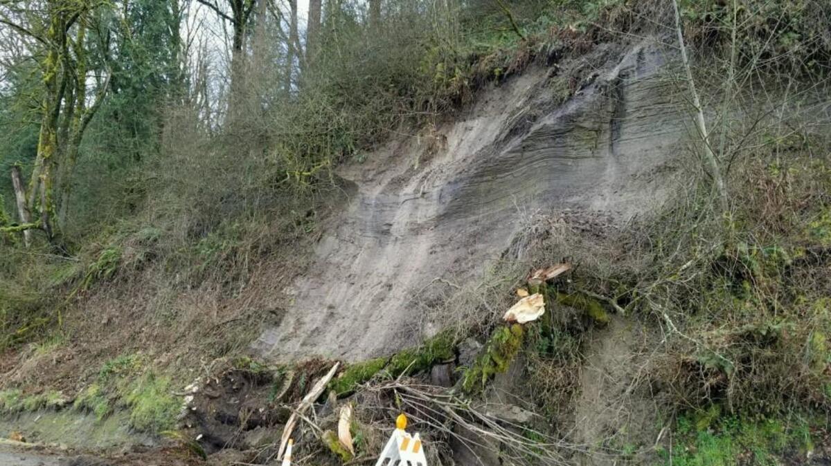Dirt and debris covered half of East Pioneer Way in Puyallup after the adjacent steep hillside partially collapsed