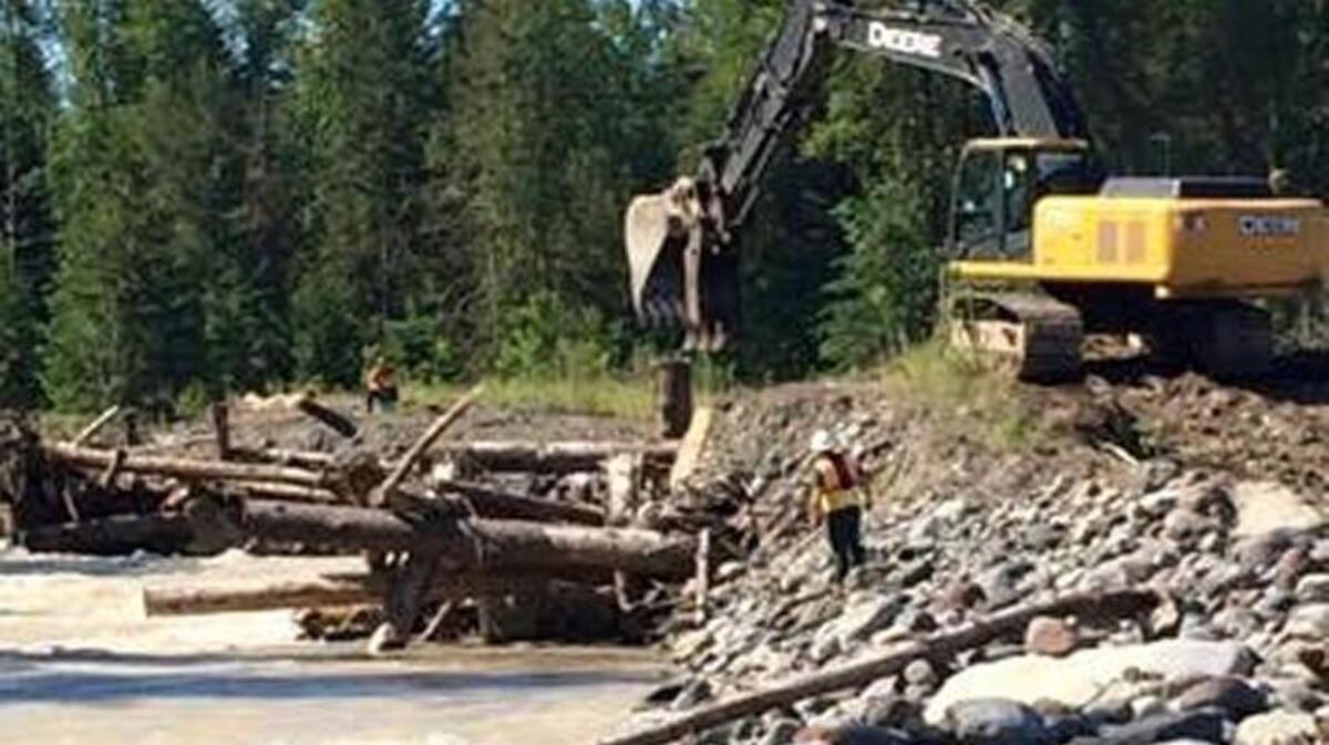 A Pierce County Public Works backhoe clears a logjam in the Puyallup River on Sunday that trapped and killed a Graham inner tuber Saturday night.