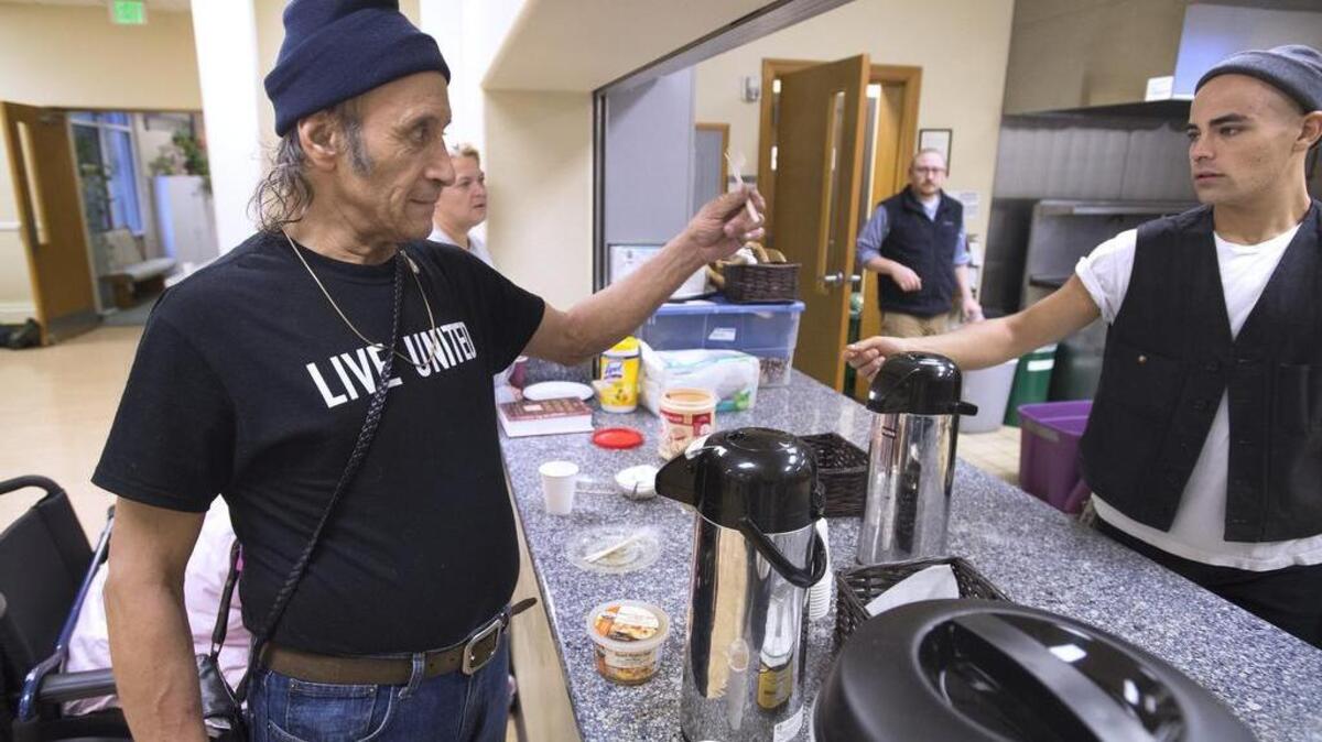 Sergio Jamarillo gets a fork last December from Interfaith Works Winter Warming Center support staffer Max Goldsmith after preparing a bowl of soup and hot chocolate for lunch at Temple Beth Hatfiloh — one of three downtown Olympia churches that split the daily daytime centers. “We feel lucky to have some meals and some help. God bless America,” Jamarillo said.