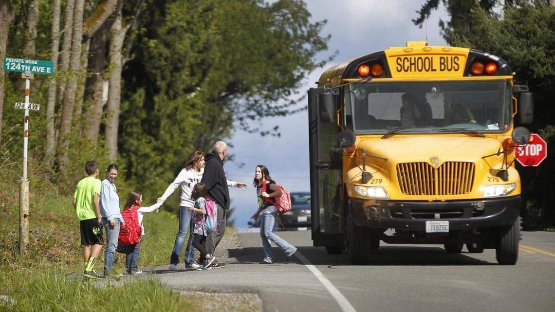 Parents greet their children as they get off the school bus along 224th Street in Graham on Wednesday, April 29, 2015.