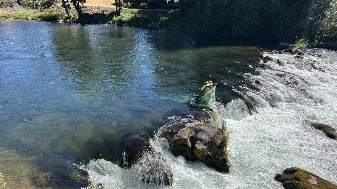 Two men are seen standing in a submerged boat caught in rocks in the middle of the Santiam River in Oregon.