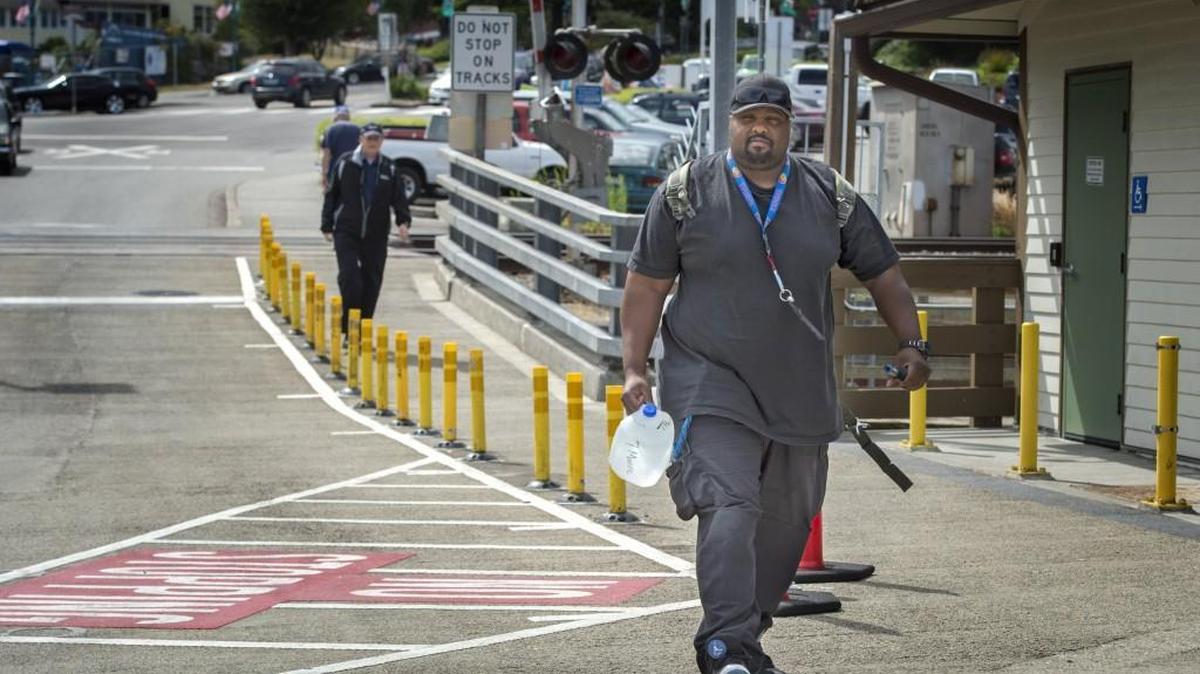A worker at the Special Commitment Center carries a gallon jug of water last week at the Steilacoom Ferry Dock to catch the ferry for McNeil Island.