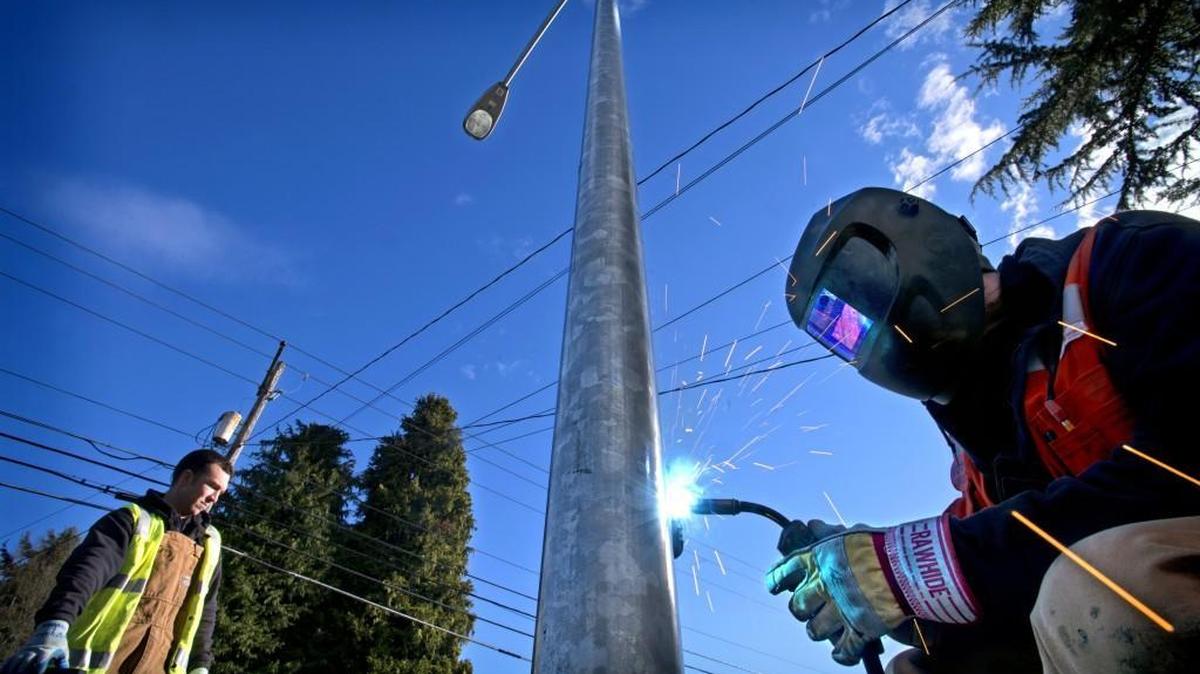 Sean Veley, left, of Tacoma Power worked to rewire damaged streetlights and weld access plates in 2014. The Tacoma City Council has approved rate increases that are divided between the fixed cost of access to power and the variable cost linked to how much a consumer uses.