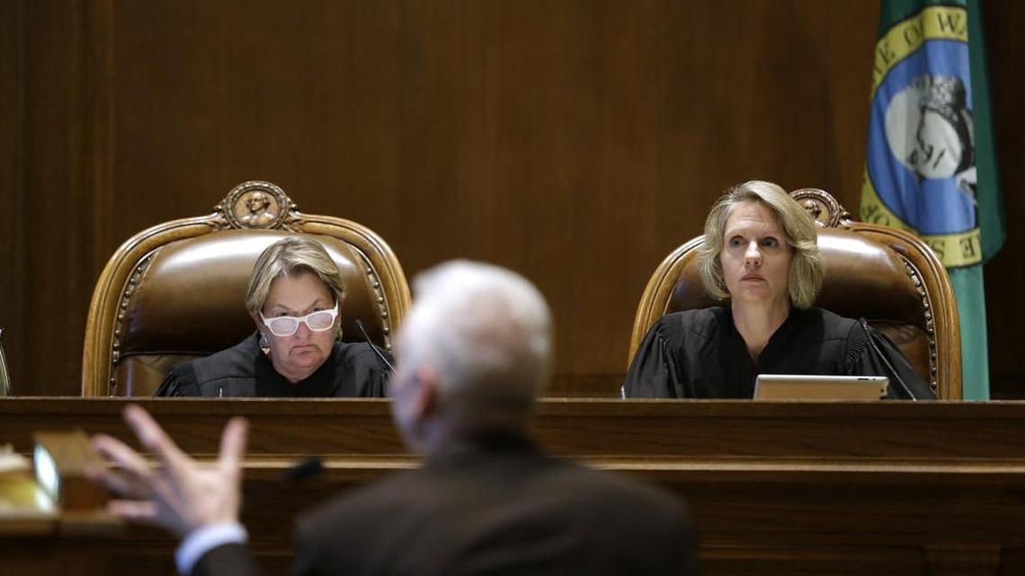 
Supreme Court Justices Susan Owens, left, and Debra Stephens listen to Thomas Ahearne, attorney for the coalition that sued the state over education funding, during a hearing before the state Supreme Court on Sept. 3, 2014, in Olympia. Last week, the court ordered the state to pay a fine of $100,000 per day over the Legislature’s failure to come up with a detailed education funding plan.
