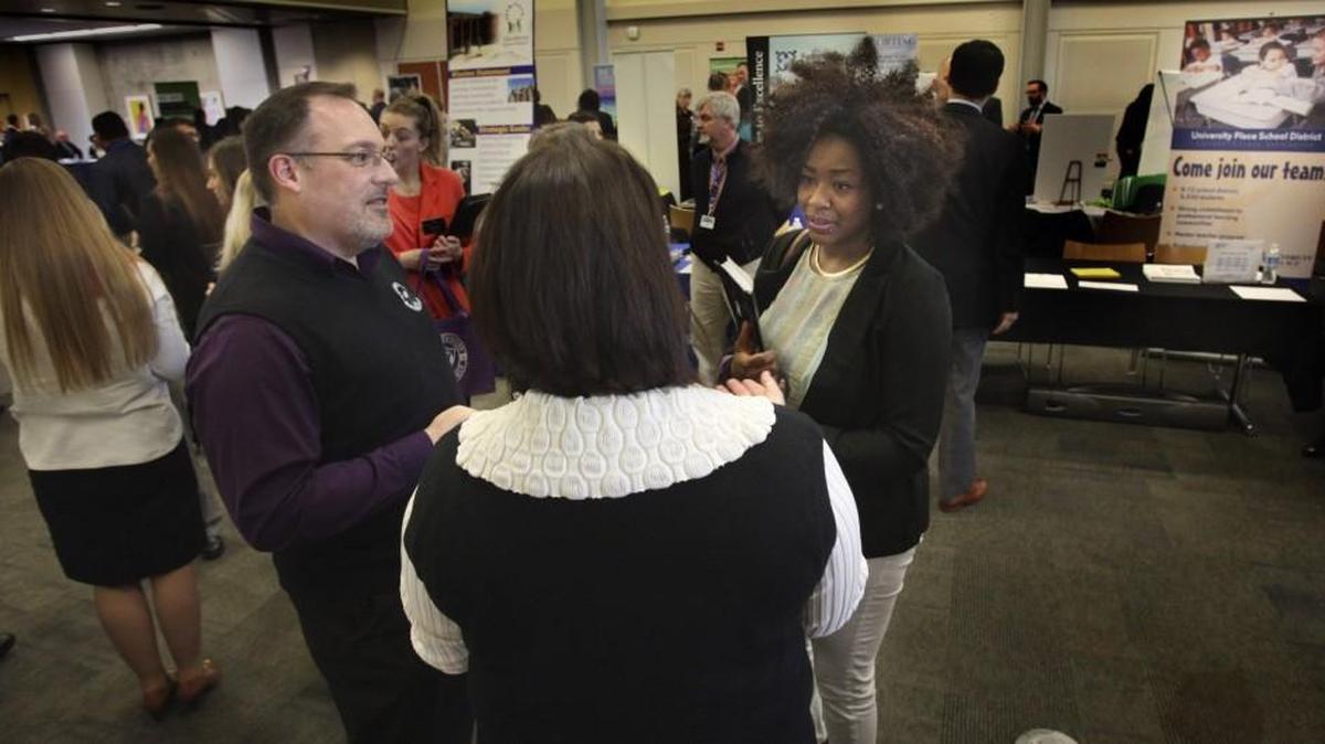 Joe Bremgartner, executive director for human resources at North Thurston Public Schools, talks about job opportunities with University of Washington student E’Braune Crowder during a job far at UW Tacoma on March 16. School districts are having to aggressively pursue candidates to fill teaching positions, which means many applicants at career fairs like this one are offered jobs on the spot, Bremgartner says.