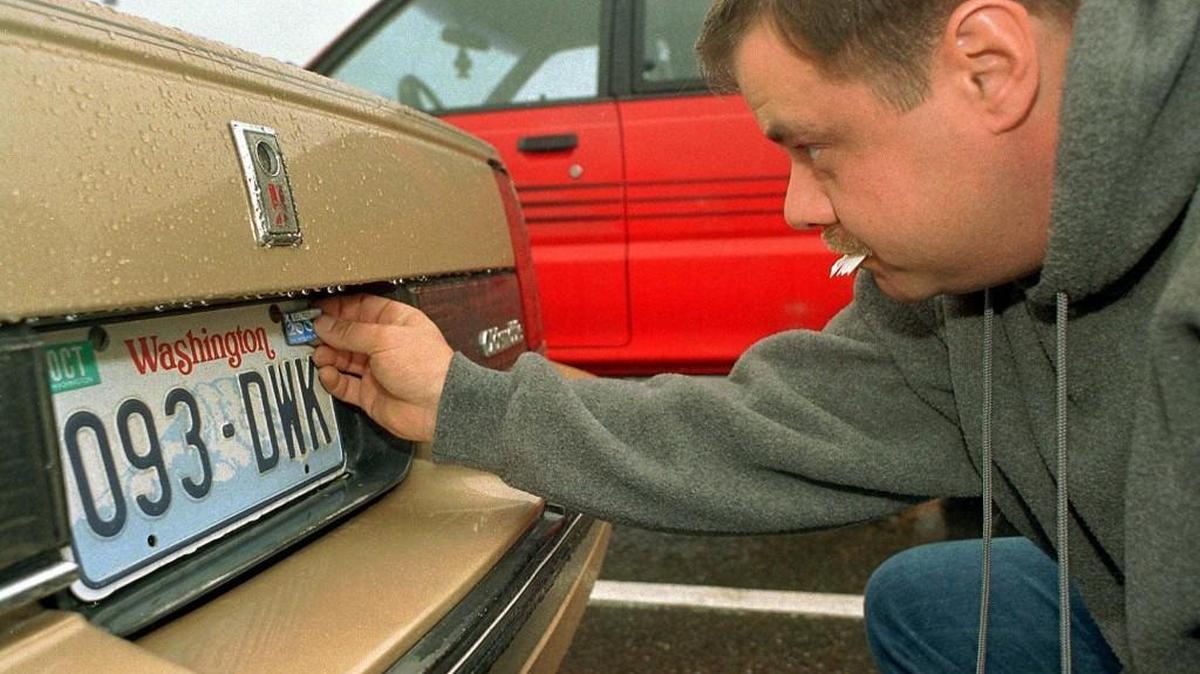 Jeff Jackson affixes new tabs to the plates of his 1985 Oldsmobile, after paying $32 to renew the license of his car in 1999 in Lacey. Sound Transit won the right to increase tab fees, but the way it calculates car values is under review in the Legislature.