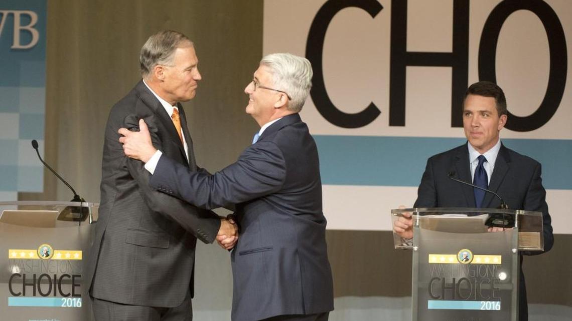Washington Gov. Jay Inslee, left, shakes hands with challenger Bill Bryant before the two debate at Spokane Falls Community College on Wednesday in Spokane. Moderator Sean Owsley of KHQ-TV is at right.