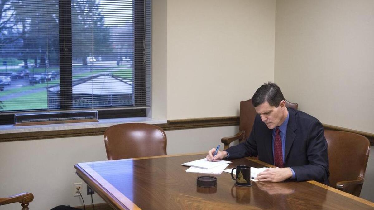 Washington State Auditor Troy Kelley looks over paperwork in the auditor’s conference room on the Capitol Campus in Olympia in 2015. Now he’s on trial.