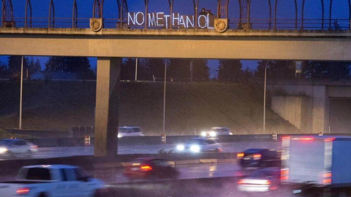 Opponents of a proposed methanol refinery on the Tacoma Tideflats use an illuminated sign to make their point on a pedestrian walkway over Interstate 5 on Feb. 19.