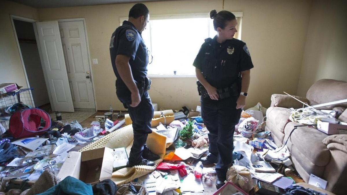 Tacoma Police officers Sam Lopez, left, and Shelbie Boyd on Thursday check out the living room where transients have been living in an abandoned house in the Hillsdale neighborhood in Tacoma on Thursday. They were at the house to provide security for code compliance workers.