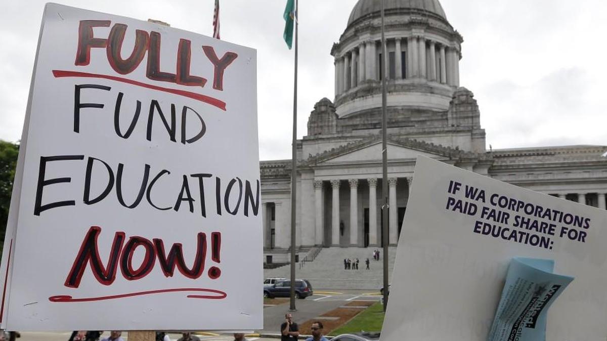 A small group of demonstrators stand on the steps of the Temple of Justice and in view of the Legislative Building in Olympia as they advocate for more state spending on education prior to a hearing before the state Supreme Court in 2014.