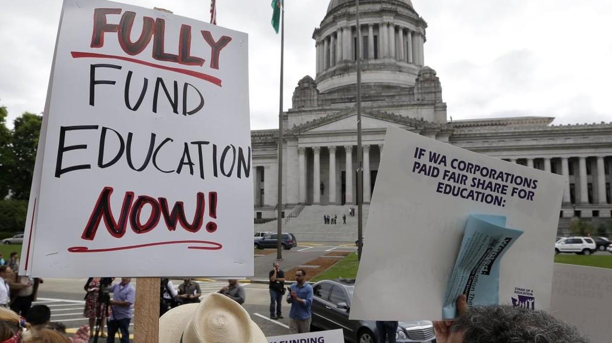 A small group of demonstrators stand on the steps of the Temple of Justice and in view of the Legislative Building as they advocate for more state spending on education prior to a hearing before the state Supreme Court Wednesday, Sept. 3, 2014, in Olympia, Wash.