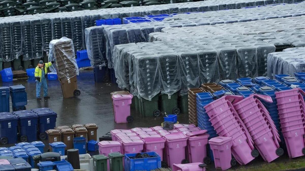 A worker at the Tacoma landfill puts together garbage and recycling containers. Tacoma residents soon could recycle glass in the same blue container as plastic, cardboard and other materials, instead of having to keep them separated.