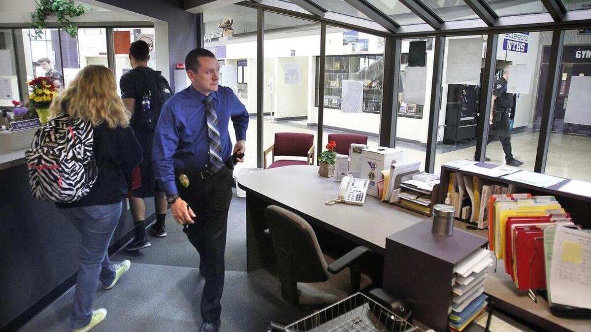A Lacey police detective passes through the office at North Thurston High School as a school resource officer walks the hallway on April 30.
