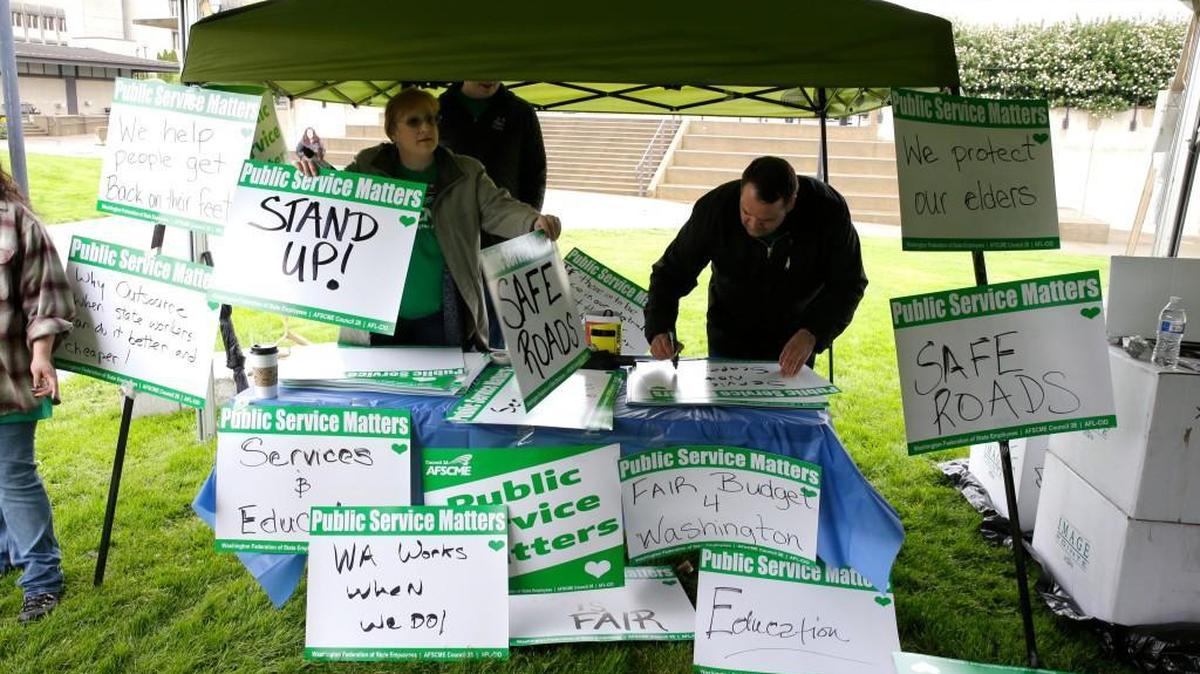 Workers prepare signs, Wednesday, April 19, 2017, during a rally held by the American Federation of State, County and Municipal Employees at the Capitol in Olympia, Wash. The rally was held to urge lawmakers to including funding for new labor contracts in the budget currently being put together in the Legislature. (AP Photo/Ted S. Warren)