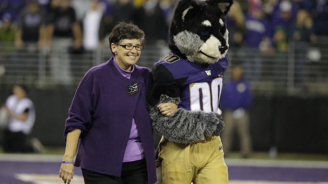 Ana Mari Cauce, the new president of the Univeristy of Washington, walks with Washington mascot “Harry the Husky,” after she was introduced at an NCAA college football game against Oregon, Oct. 17, in Seattle.
