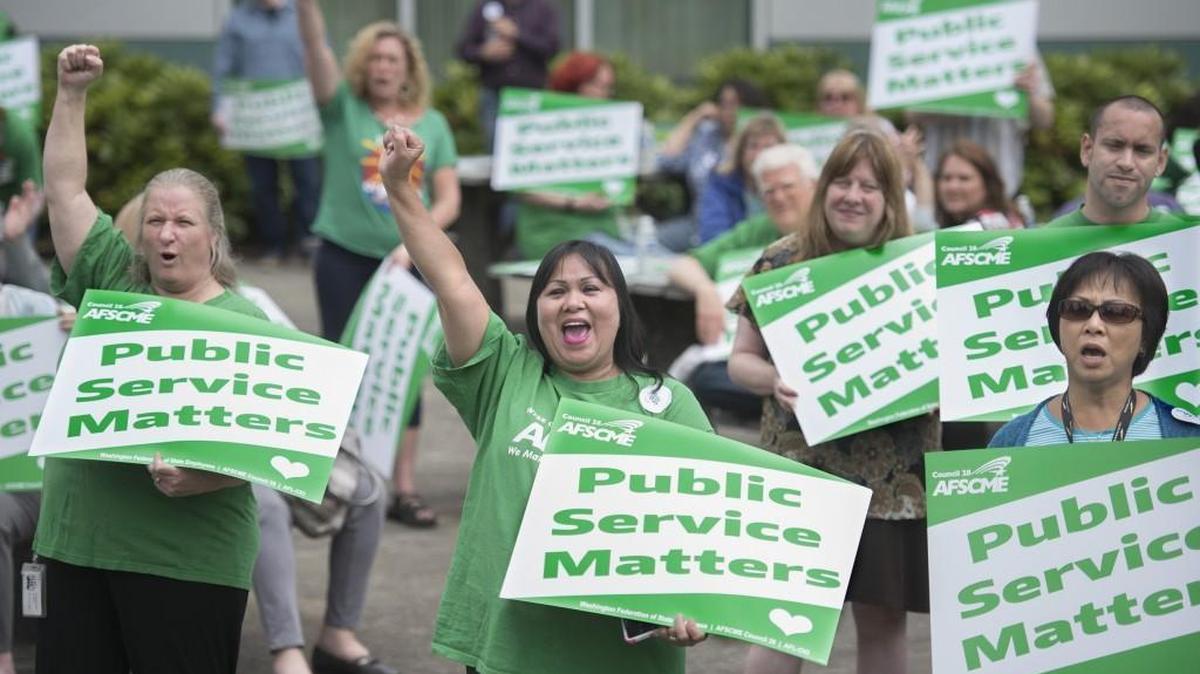 Kellie Klimcazk, left, and Diosy Page, center, cheer during a rally for the Washington Federation of State Employees at the Labor and Industries Building in Tumwater in 2017.