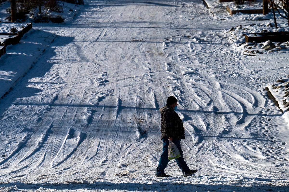 A man walks along Tacoma Avenue South past an unplowed 15th Street near downtown Tacoma on Monday afternoon.