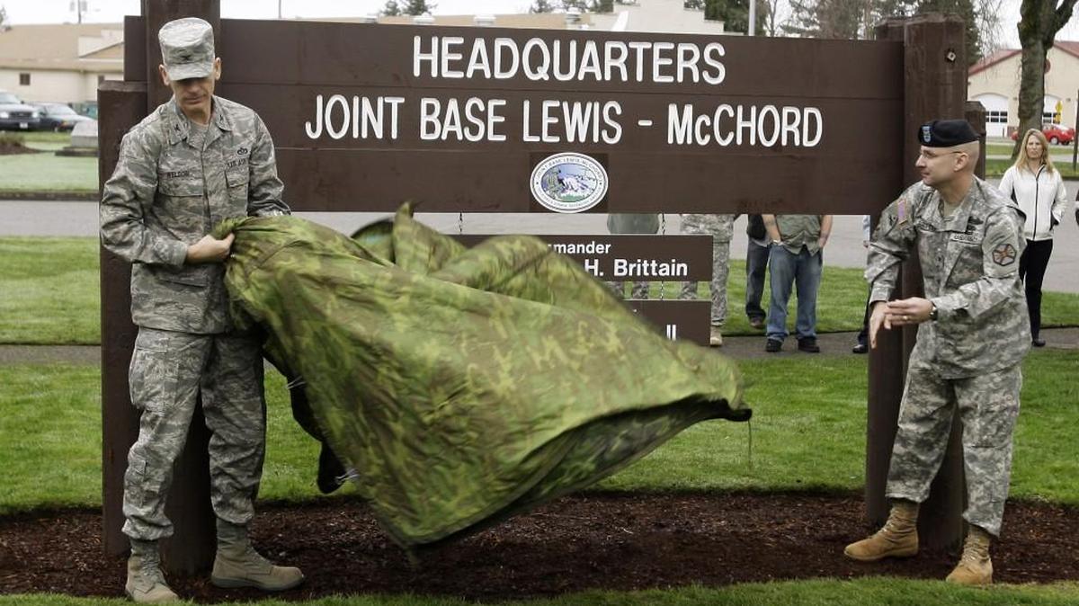 U.S. Army Col. Thomas Brittain, right, and Air Force Col. Kenny Weldon, left, unveil a new sign for Joint Base Lewis-McChord on Feb. 1, 2010. The base is sending nonessential personnel home early Thursday and having them report to work later Friday as a fall wind and rain storm approaches the South Sound.