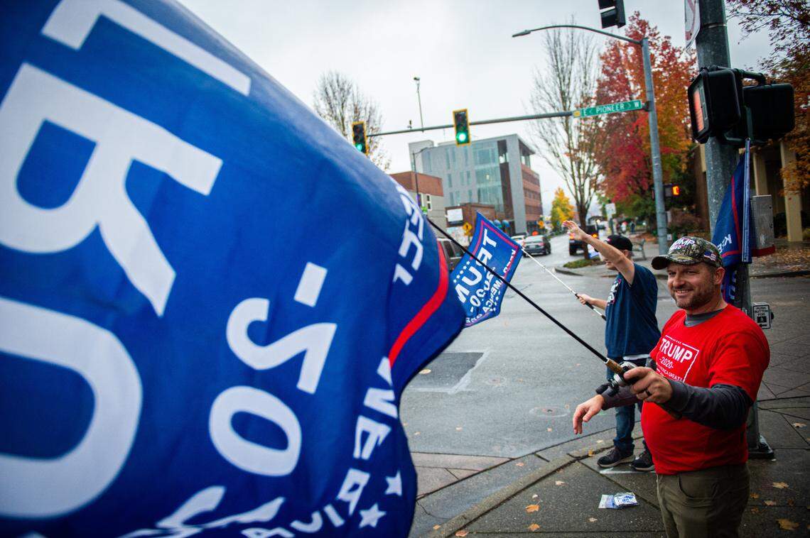 Tim Mellema, front, and Nate Prutzman wave flags in support of Donald Trump in downtown Puyallup, Wash., on Tuesday, Nov. 3. 