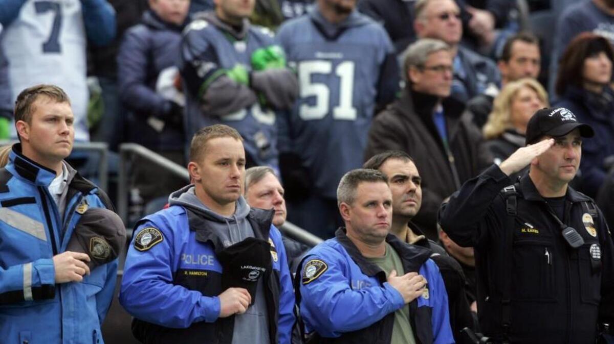 Lakewood police officers stand on the sidelines during the national anthem before the start of a Seahawk home game against San Francisco in 2009. The officers were invited to participate in the wake of the murder of four fellow Lakewood officers several days earlier.