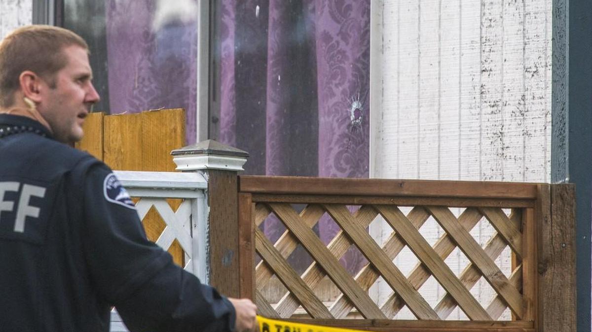 Pierce County Sheriff's Deputy Mike Doyle adjusts police tape by a bullet hole in the Bonney Lake house where Linda Green was critically injured by a neighbor firing his pistol at a fleeing car thief on Nov. 3.