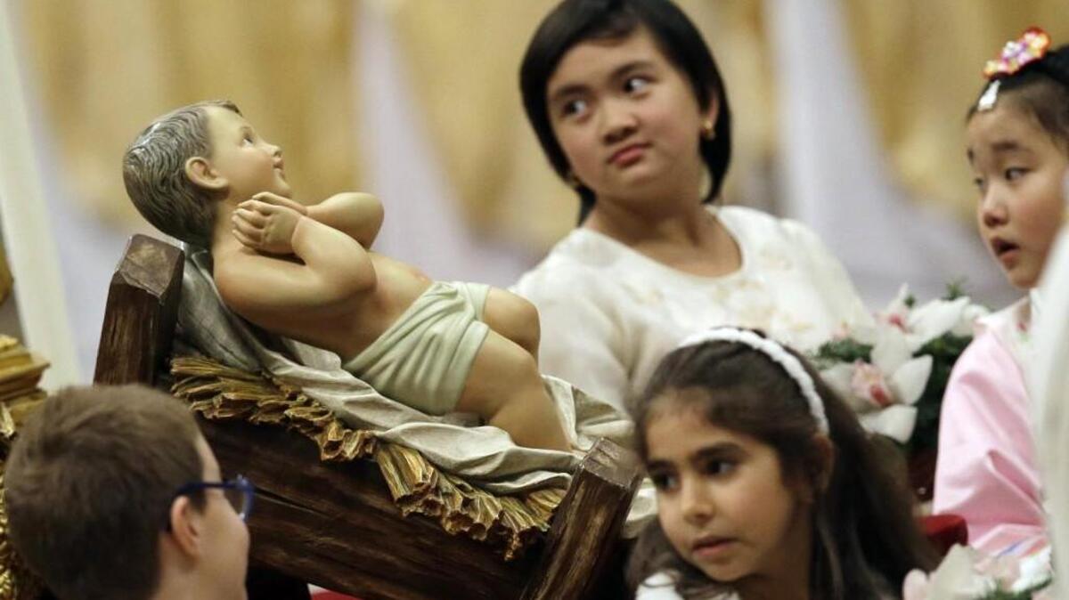 Children look at a statue of Baby Jesus during the Christmas Eve Mass celebrated by Pope Francis in St. Peter's Basilica at the Vatican in 2014.