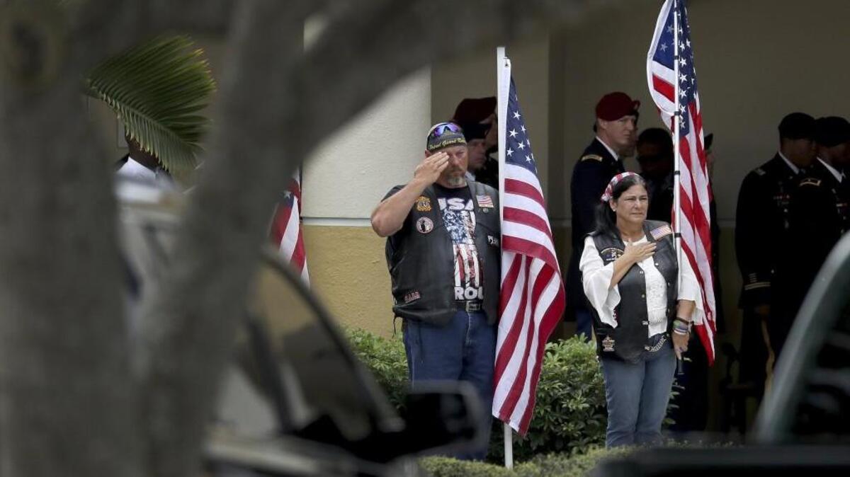 Mourners hold flags for the burial service of Army Sgt. La David Johnson at the Hollywood Memorial Gardens in Hollywood, Fla., on Saturday. Johnson was killed with three other soldiers, including Staff Sgt. Bryan Black of Puyallup, in an ambush by extremists in Niger on Oct. 4.