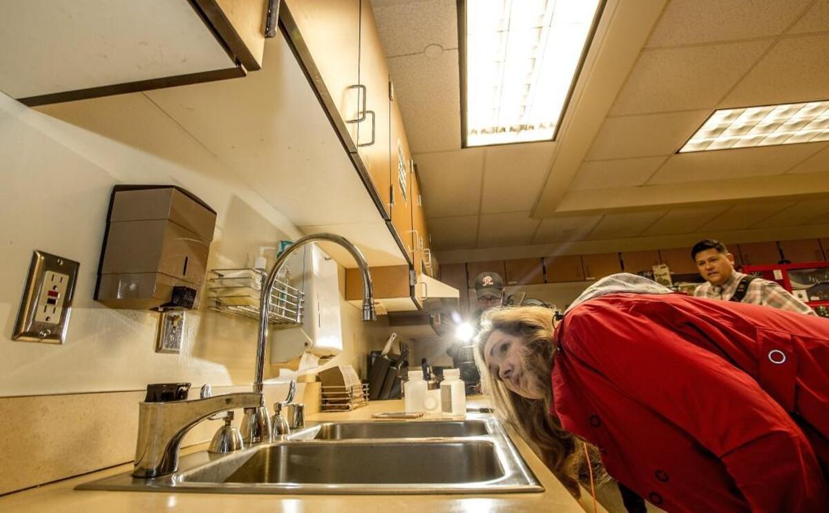 Donna McNeal, from Orion Environmental Services of Federal Way, examines a faucet before taking a sample to test for lead in a Tacoma school in 2016.