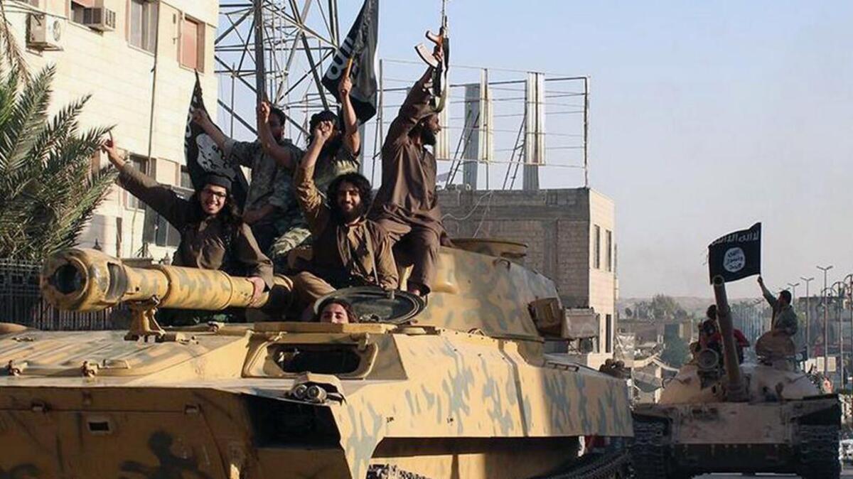 In this undated image posted by the Raqqa Media Center in Islamic State-held territory, fighters from the Islamic State group ride tanks during a parade in Raqqa, Syria.