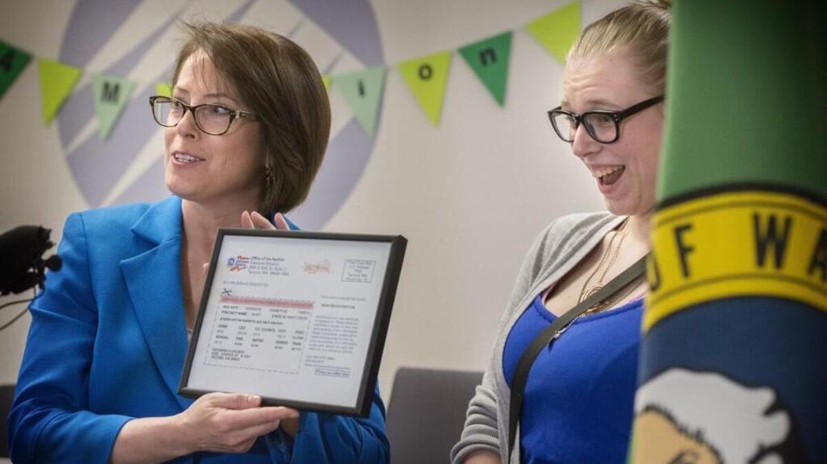 Katarina Gruber, who was then an 18-year-old Clover Park High senior, seems happy to receive a display version of her voter registration card from Pierce County Auditor Julie Anderson at the Pierce County Annex in April 2016. Gruber was honored as Washington’s 4 millionth voter, and relished the chance to vote in her first presidential election.