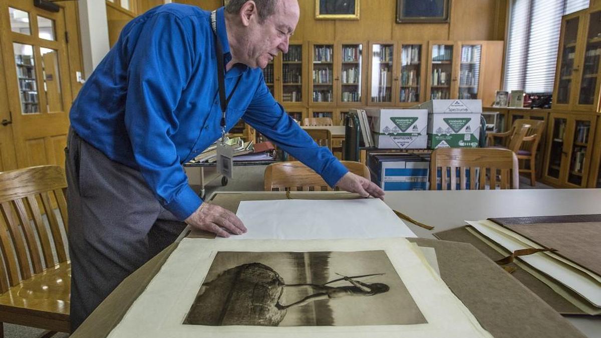 Brian Kamens, supervisor of the Northwest Room who has worked there since 1982, looks at the library's collection of Edward Curtis photographs of Native Americans from the early1900s.