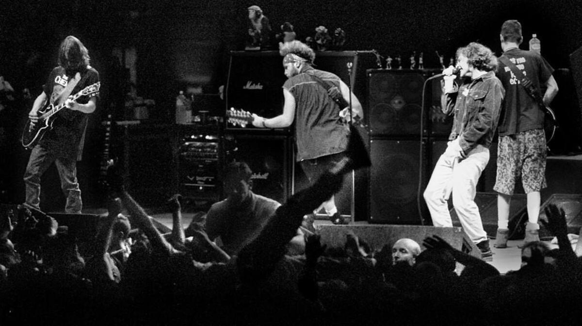 A mosher throws an approving leg to the air as Pearl Jam (lead singer Eddie Vedder, bass guitarist Jeff Ament, center, guitarist Mike McCready, far left, and guitarist Stone Gossard, far right) open their Seattle concert tour at the Seattle Center Arena. 11/7/93.