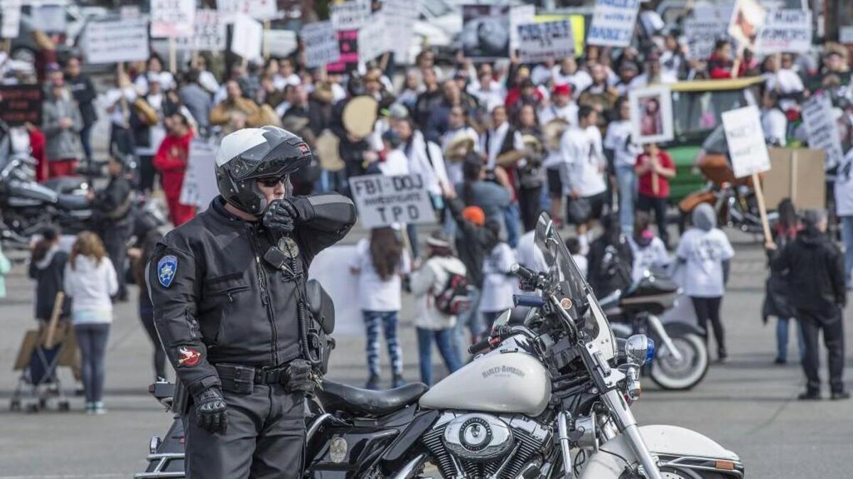 A Tacoma police officer keeps an eye on protesters as they walked through Tacoma in March to take a stand against the police shooting death of Jacqueline Salyers. A month later, many of Salyers’ supporters spoke at City Hall. A prosecutor’s office investigation has since determined her killing to be justifiable homicide.