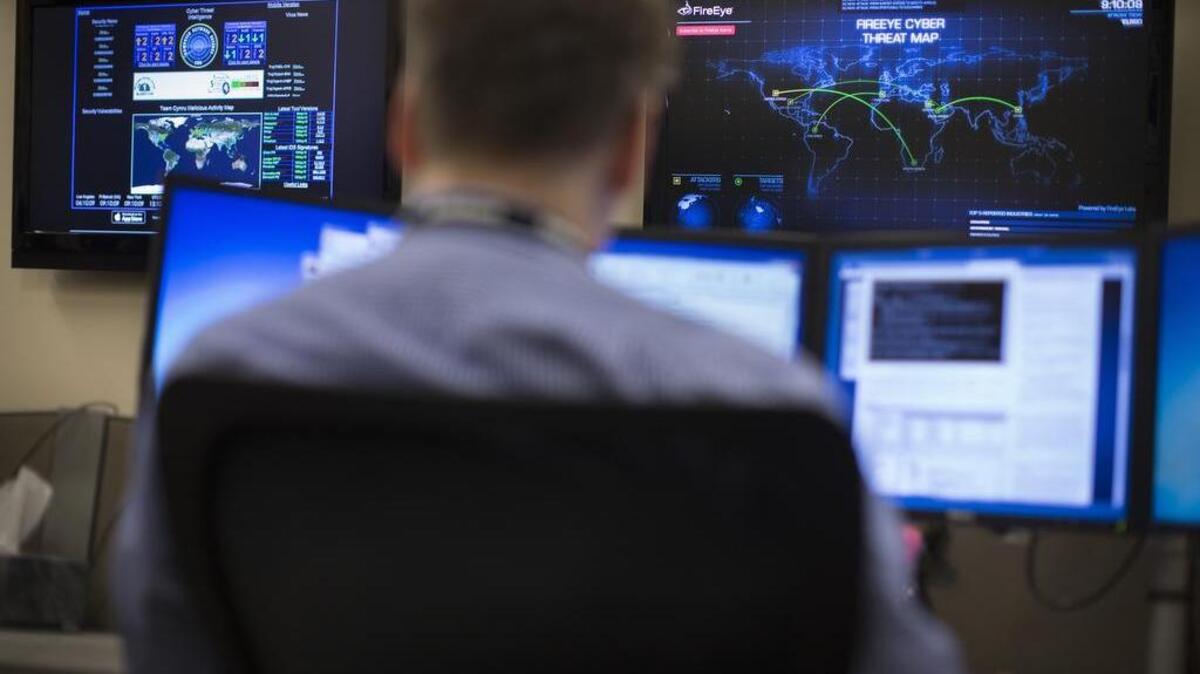 A security specialist works at a computer station with a cyber threat map displayed on a wall in front of him in the Cyber Security Operations Center at AEP headquarters in Columbus, Ohio.
