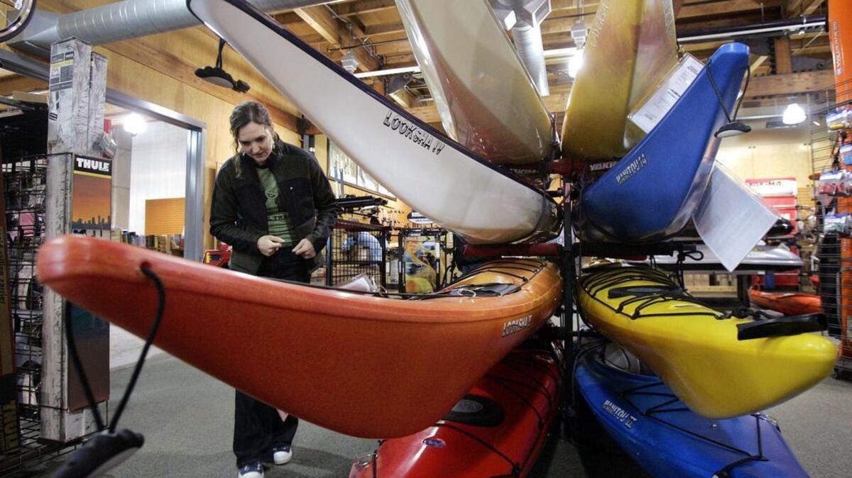 A customer looks over sea kayaks at the REI store in Seattle. The Kent-based outdoor retailer will buck Black Friday 2015 and close its 143 stores on the day after Thanksgiving, giving workers a paid day off.